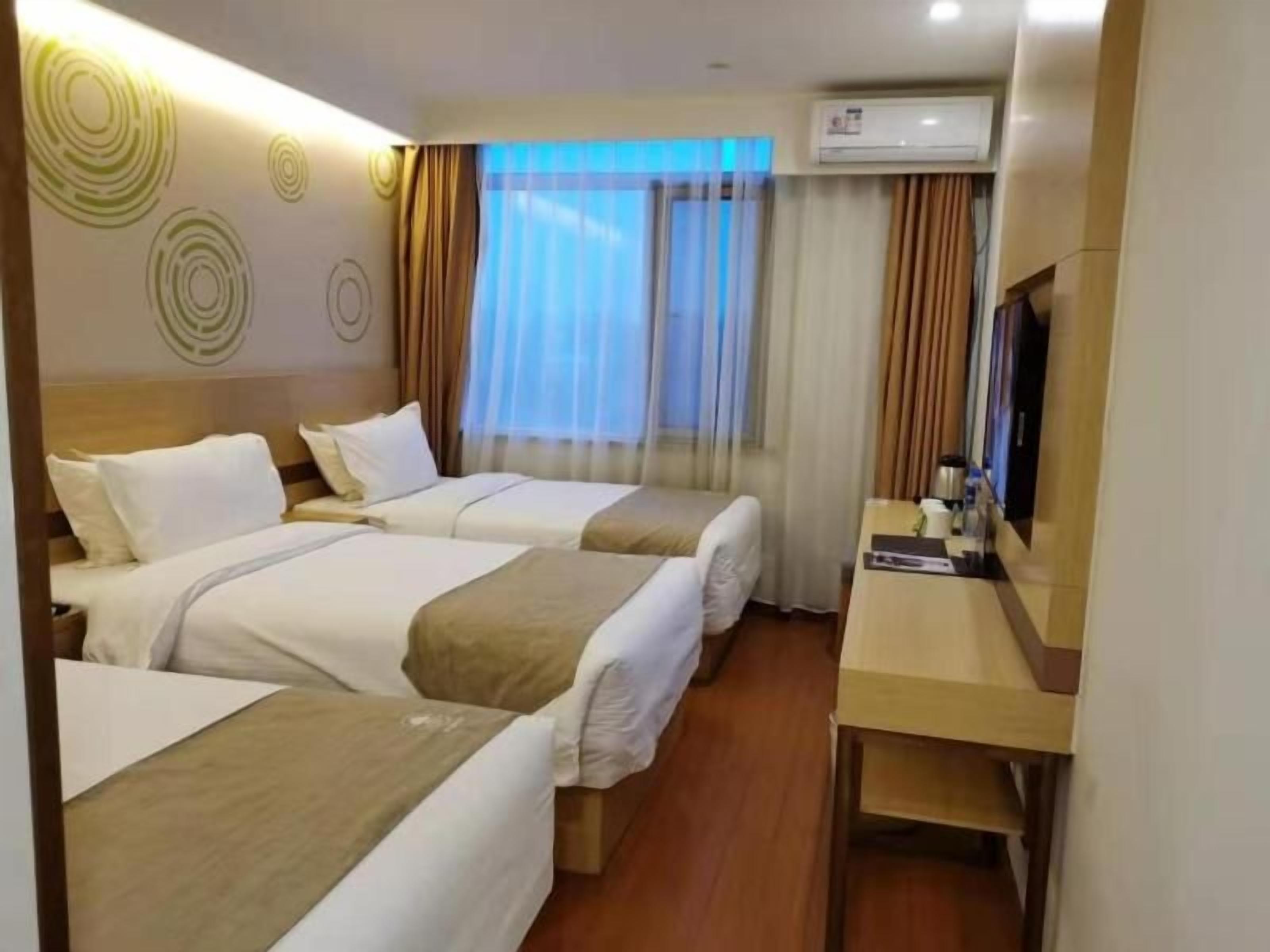 A hotel room with two beds, a desk, and a television.