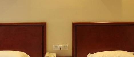 A hotel room with two beds, a nightstand with a phone, and two framed pictures on the wall.