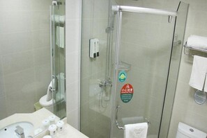 Une salle de bain avec une douche à parois de verre, un lavabo avec des articles de toilette et des toilettes.