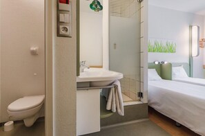 Et hotelværelse med toilet, håndvask og seng.