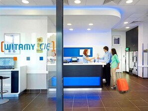 A reception area with a desk, a computer, and a sign that reads "WITAMY CIE". - Ibis Budget Warszawa Reduta (Warsaw)