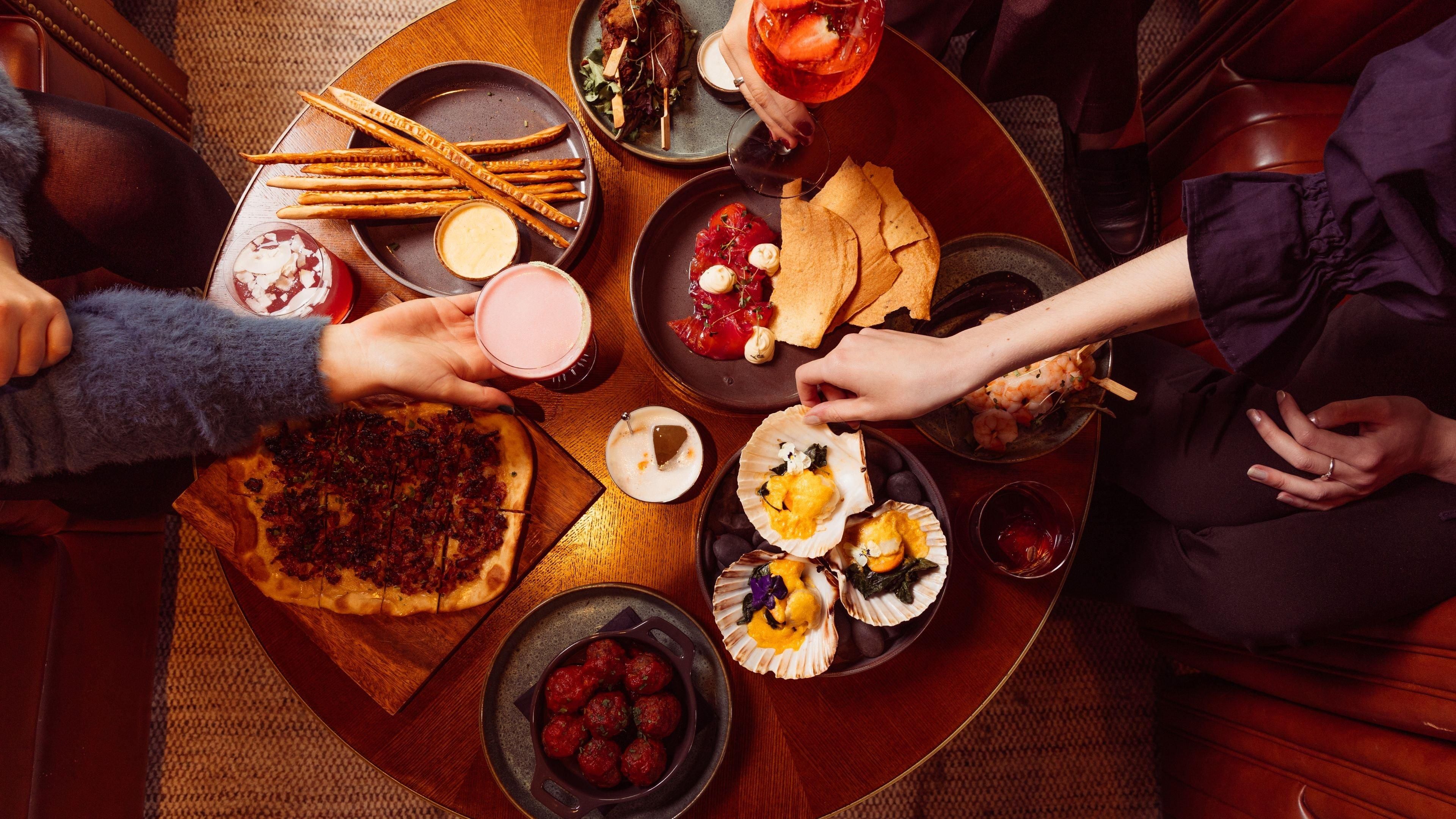 A round table with various dishes, including pizza, seafood, and breadsticks, suggesting a communal dining setting.