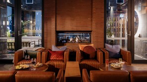 A modern lounge area with leather seating, a fireplace, and a glass wall offering a city view. - Voco Auckland City Centre (Auckland)