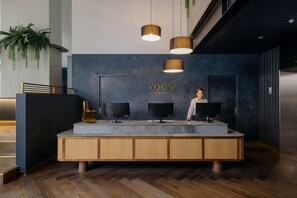 A reception desk with a dark blue wall, two monitors, and a sign that reads 'VOCO AN ING HOTEL'. - Voco Auckland City Centre (Auckland)