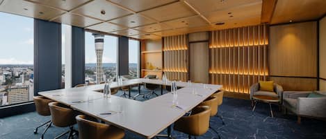 A conference room with a large table, chairs, and a city view.