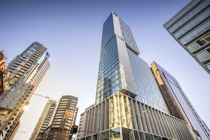 Um edifício alto com fachada de vidro moderna, cercado por outros edifícios imponentes.