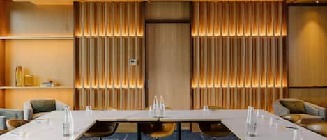 A conference room with a long table, chairs, and a wooden panel wall with vertical slats.