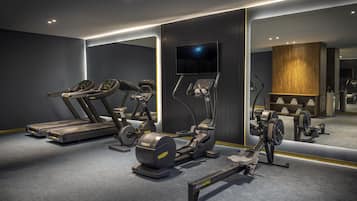 Un gimnasio moderno con cintas de correr, elípticas y máquinas de remo.