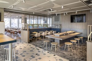 A modern interior with a bar area, seating, and large windows. - Holiday Inn Express Auckland City Centre (Auckland)