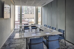 A conference room with a long table, blue chairs, and a view of buildings through large windows. - Holiday Inn Express Auckland City Centre (Auckland)