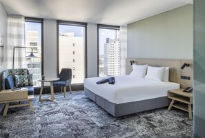 Une chambre d’hôtel avec un lit, une chaise, une petite table et une table de chevet.