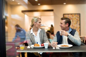 Two people dining at a table with plates of food and drinks. - Holiday Inn Express Auckland City Centre (Auckland)