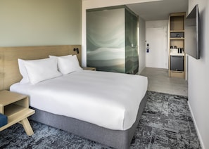 A hotel room with a bed, bedside table, a glass partition, a small kitchenette, and a television. - Holiday Inn Express Auckland City Centre (Auckland)