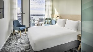 A hotel room with a large bed, a chair, a small table, and a view of the city. - Holiday Inn Express Auckland City Centre (Auckland)