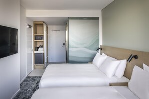 Ein Hotelzimmer mit Bett, Fernseher, Minibar und einer Tür zum Badezimmer.