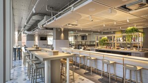 A modern bar area with high stools, a counter with bar stools, and a bar stocked with bottles. - Holiday Inn Express Auckland City Centre (Auckland)