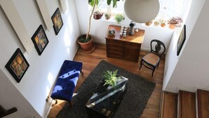 Een gezellige woonkamer met een blauwe bank, een houten salontafel met een plant en een trap naar een hoger niveau.