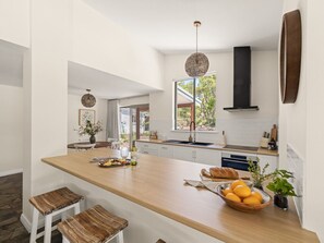 Une cuisine moderne dotée d’un îlot central, de meubles blancs et offrant une vue sur l’extérieur.