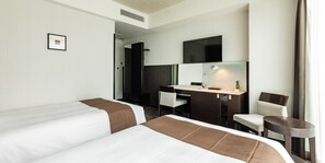 Une chambre d’hôtel avec deux lits, un bureau, une chaise, un miroir et un téléviseur.