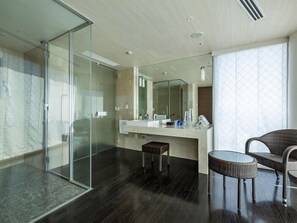 Ein modernes Badezimmer mit Duschkabine aus Glas, einem großen Spiegel, einem Waschbecken und einem Korbstuhl.