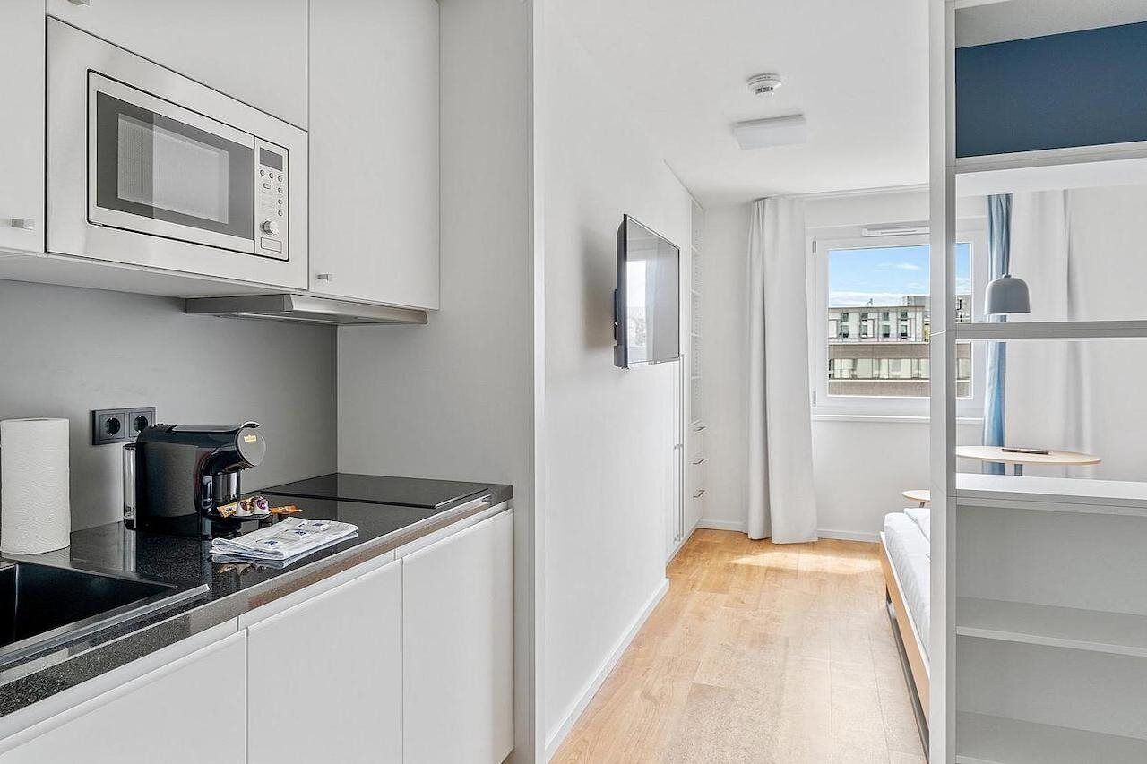 Eine moderne Küche mit Mikrowelle, Kaffeemaschine und einer kleinen Essecke mit Tisch und Stühlen.