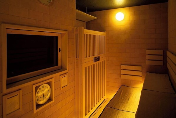 Een hotelkamer met een groot raam, een klok, een radiator en een bed.