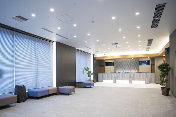 A modern lobby with seating areas, a reception desk, and a large window with blinds. - Dormy Inn Premium Nagasaki Ekimae (Nagasaki)