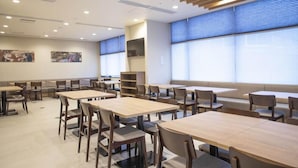 A spacious dining area with multiple tables and chairs, large windows with blinds, and artwork on the walls. - Dormy Inn Premium Nagasaki Ekimae (Nagasaki)