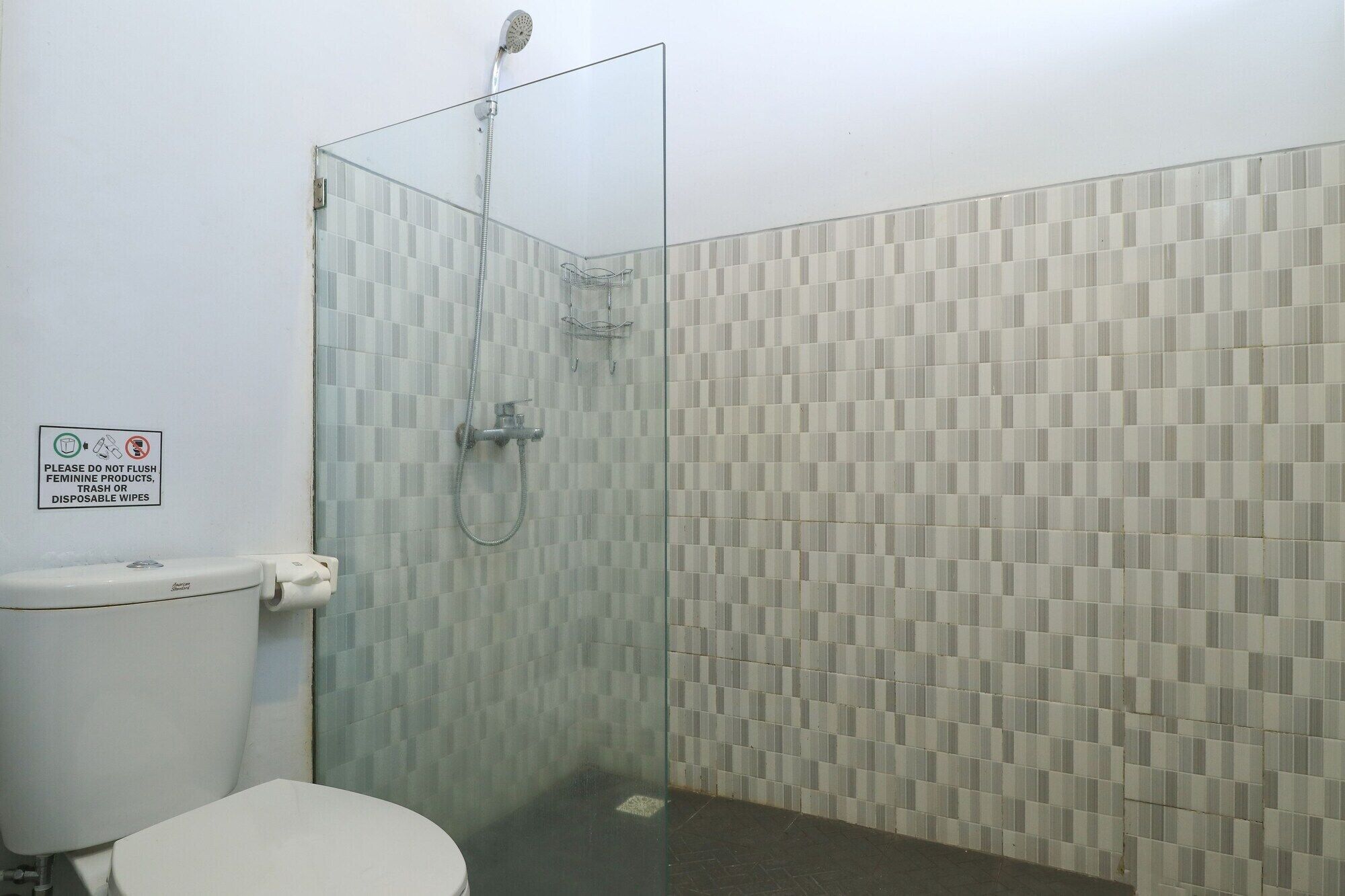 Une salle de bain avec une douche à parois de verre, des toilettes et des murs carrelés.
