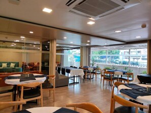 Un restaurante moderno con mobiliario de madera, ventanas amplias y vistas a la ciudad.