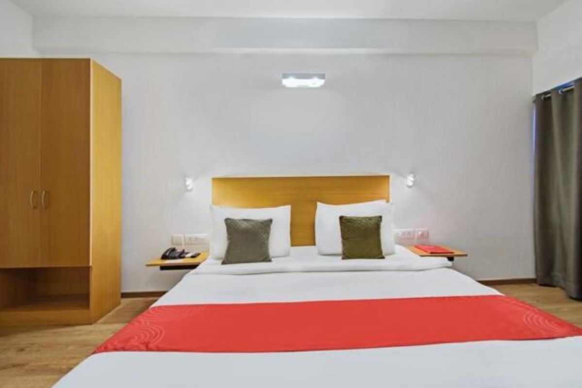 Ein Hotelzimmer mit Bett, Nachttisch, Lampe und Kleiderschrank.