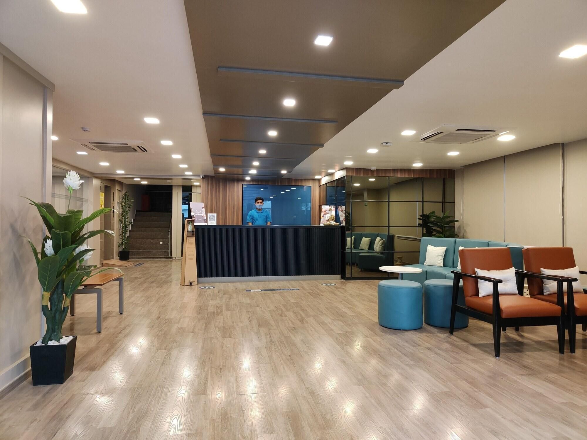 A modern reception area with a reception desk, seating area, and a staircase leading to an upper level.