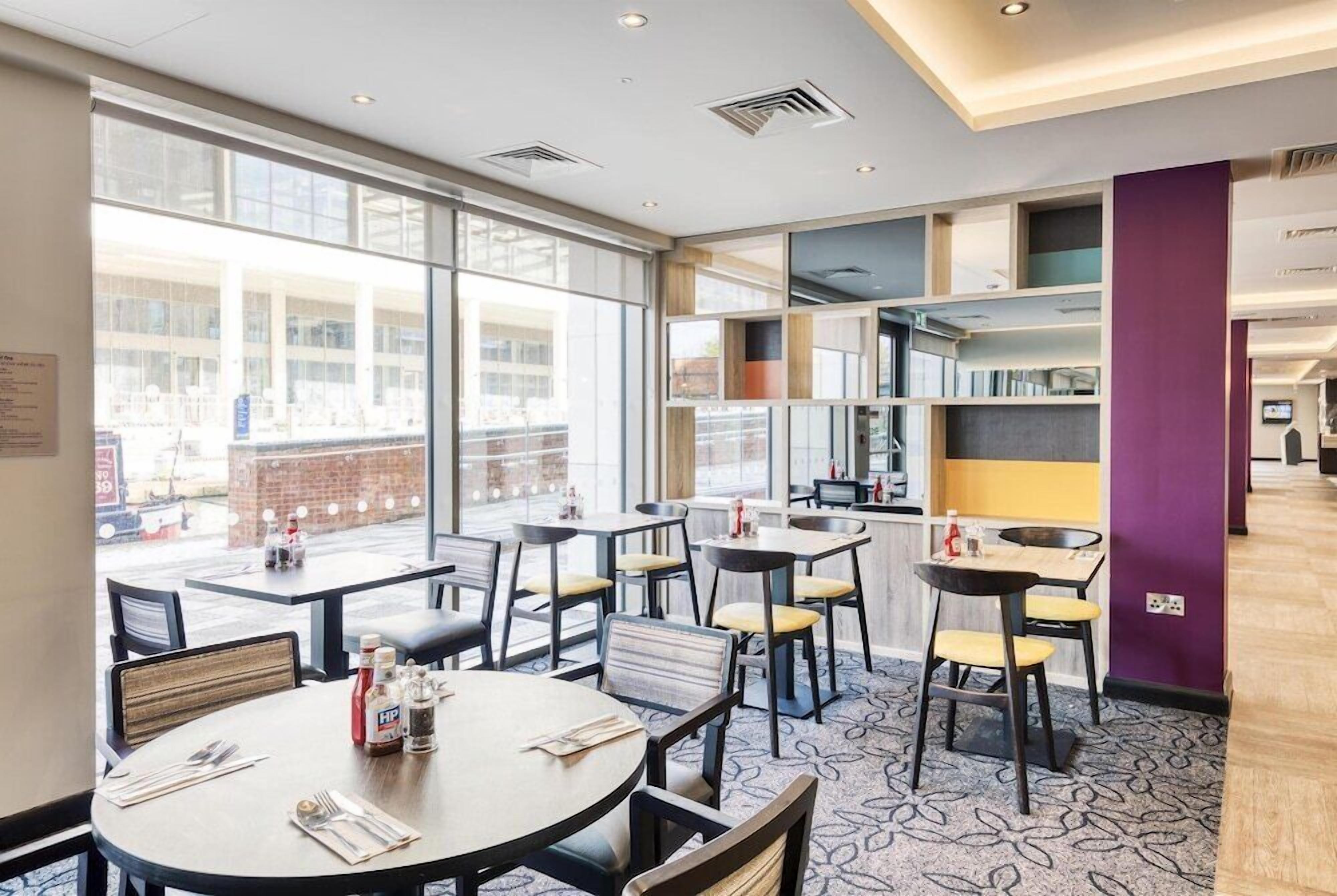 A modern dining area with round tables, chairs, and a view through large windows.