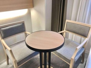 Een zithoek met een ronde tafel en twee fauteuils met hoofdsteunen.