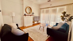 A living room with a sofa, a coffee table, a TV stand, and a plant. - Character maisonette halfway between the city and the sea (Plympton)