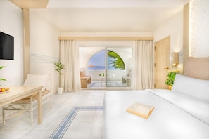 Une chambre d’hôtel comprenant un lit, un bureau, une chaise, une télévision et un balcon avec vue sur la mer.