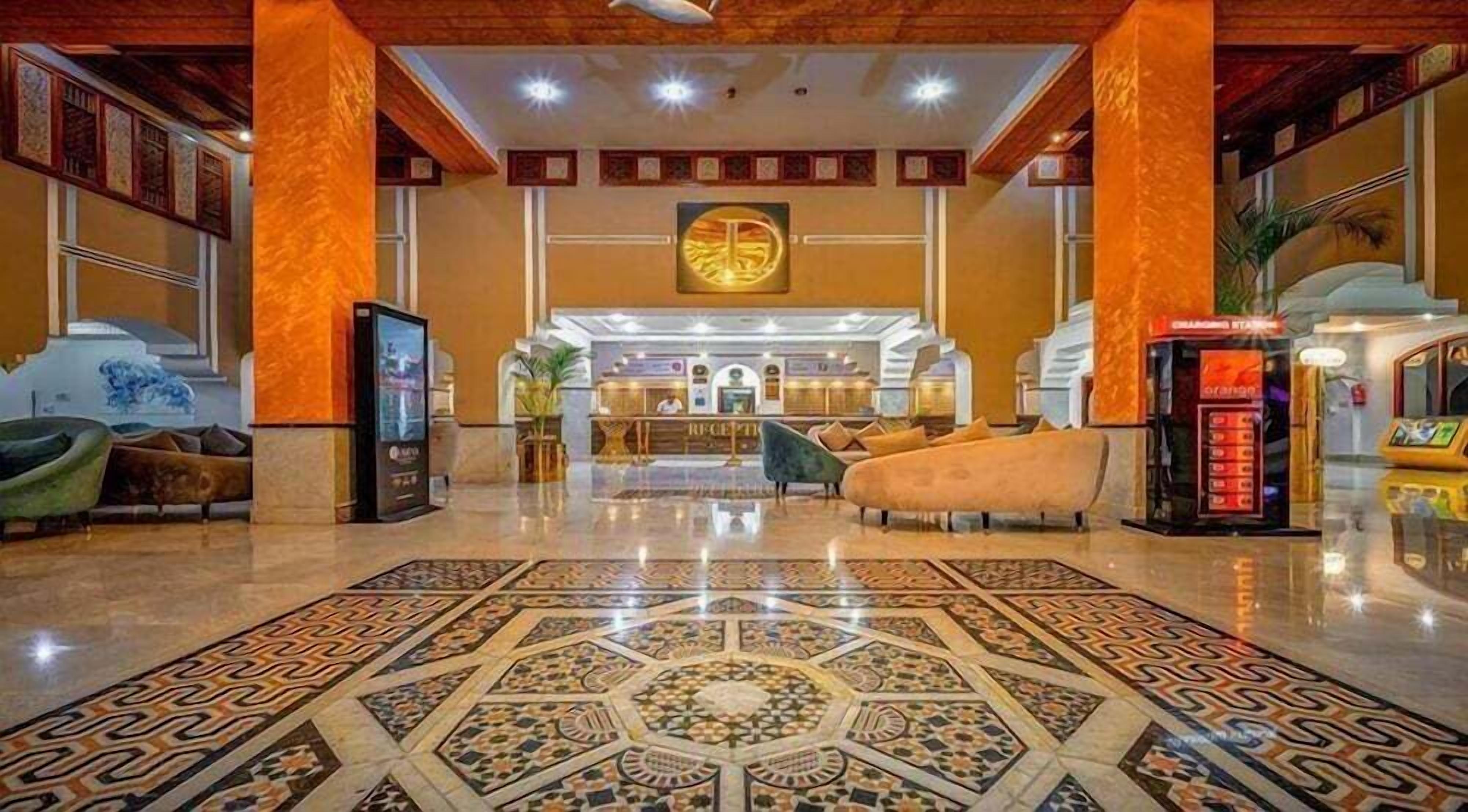 Una hall d'albergo con reception, area salotto e un motivo decorativo sul pavimento.