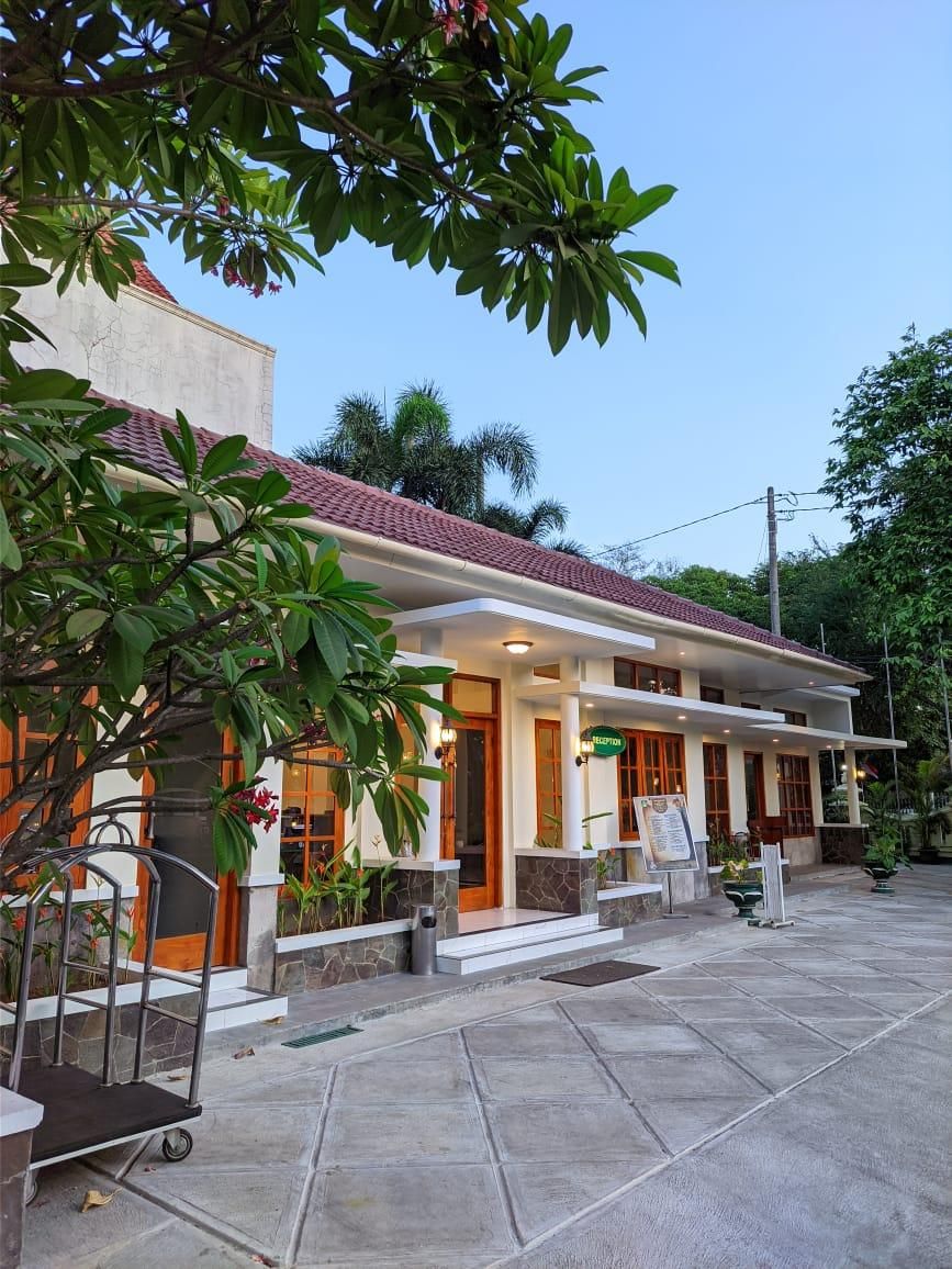 A hotel with a reception desk, a tiled patio, and a red-tiled roof.
