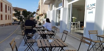 Mesa y sillas en terraza frente a un edificio con un letrero que dice "LE DUNE HOTEL".