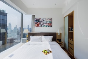 Habitación de hotel con una cama grande, vistas a la ciudad, un cuadro en la pared y un armario de madera.