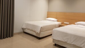 Una habitación de hotel con dos camas, un cabecero de madera, una mesita de noche y una cortina.