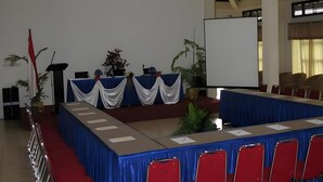 Una sala de conferències amb una taula llarga, cadires vermelles i una pissarra.