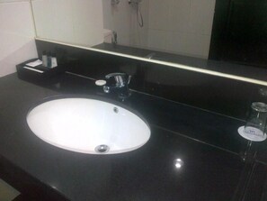 A modern bathroom with a black countertop, a white sink, and a mirror above it. - Wonua Monapa Hotel Resort (Kendari)