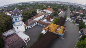 Une vue aérienne d’une ville avec une tour imposante, des rues étroites et un mélange de bâtiments résidentiels et commerciaux.