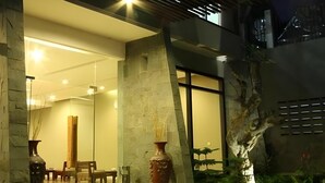 Un intérieur moderne agrémenté d’une colonne en pierre, d’un grand vase et d’un escalier menant à un balcon.