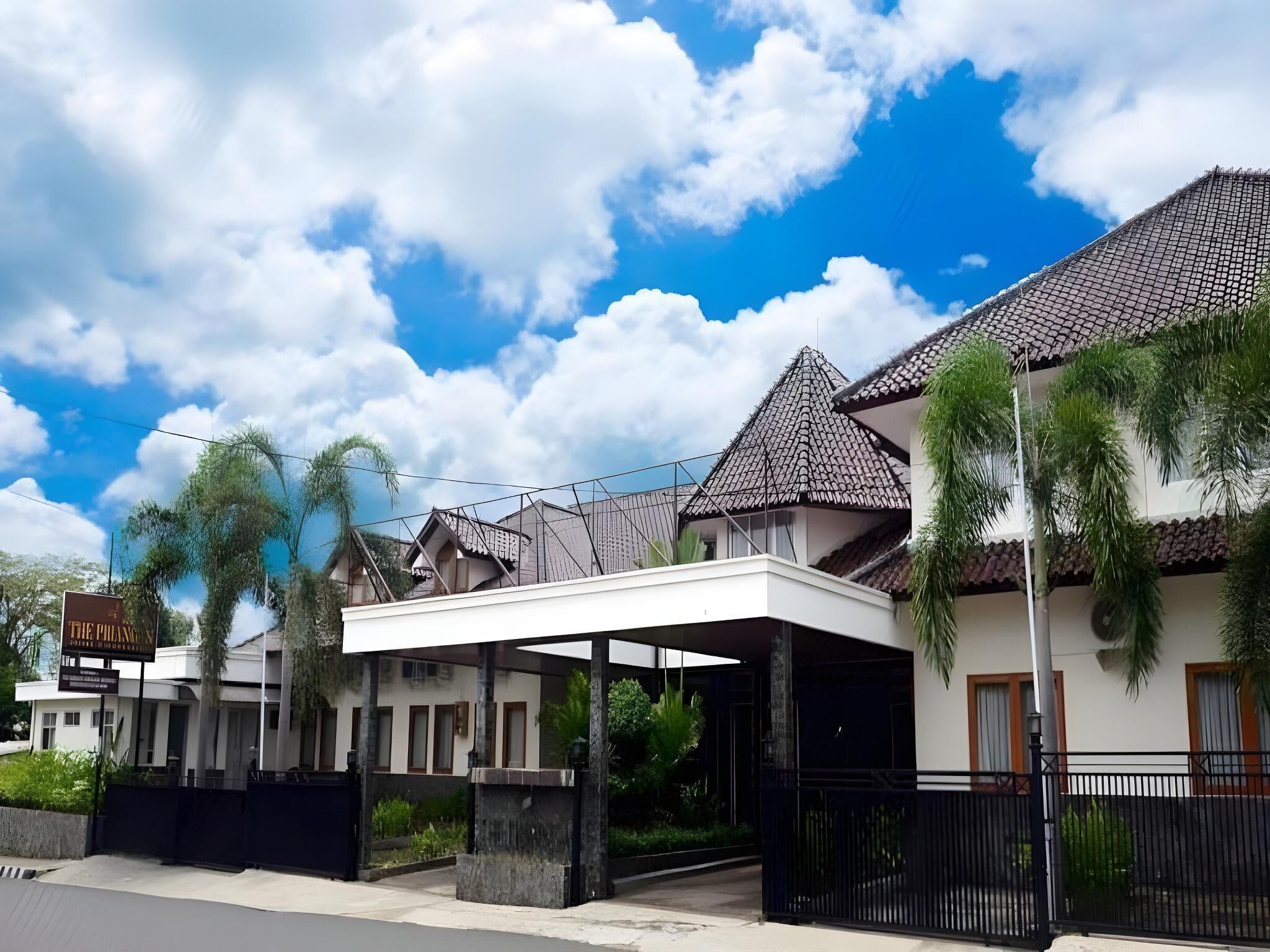 A hotel with a covered entrance, a signboard, and a tiled roof.