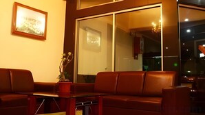 A modern living room with a sofa, a coffee table, and a potted plant. - The Priangan Boutique Hotel (Ciamis)