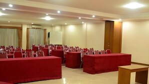 A conference room with rows of red chairs and tables, a whiteboard, and a wooden door. - The Priangan Boutique Hotel (Ciamis)