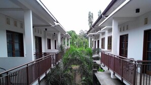 A corridor with two-story buildings, a central garden area, and a small bridge. - Rukun Resort Sentul (Citaringgul)