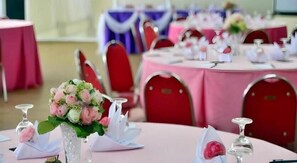 Mesas redondas con manteles rosa, sillas rojas y servilletas blancas.